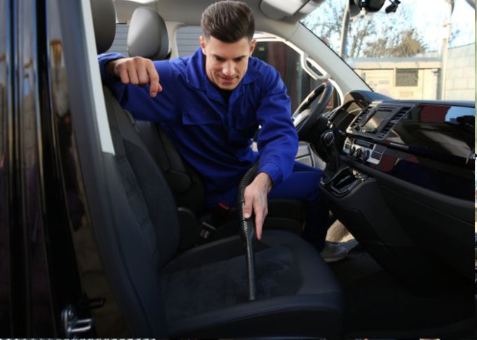 Mężczyzna pokazuje jak czyścić tapicerkę z materiału w samochodzie